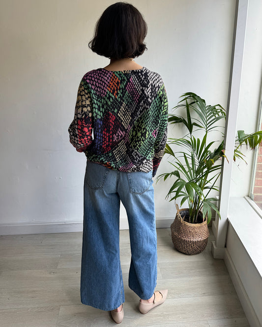 Back view of vibrant pre-loved snake print knit jumper from Jumper 1234 in shades of bold colors, featuring a cosy fabric and relaxed fit. Sized medium, perfect for layering and ideal for colder weather. 