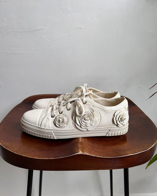 Side view of stylish pair of cream leather CC Camelia low-top trainers from Chanel