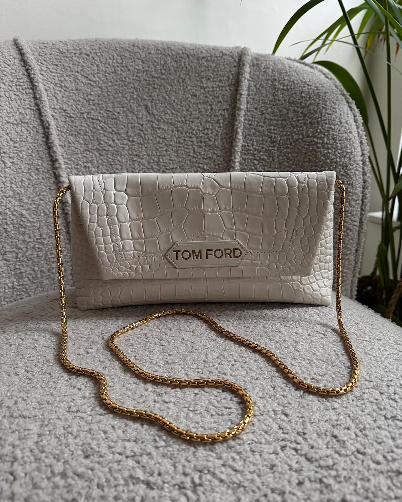 Front view of beautiful cream mock crocodile leather clutch by Tom Ford features gold hardware with a snap clasp and a leather lining. Shown with gold chain strap.