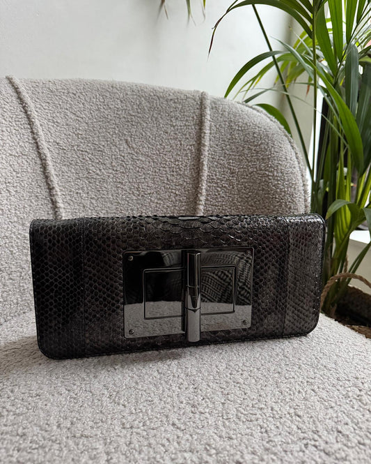 Front view of beautiful python clutch by Tom Ford features gunmetal hardware with a turn lock closure and a leather lining. Shown without strap.