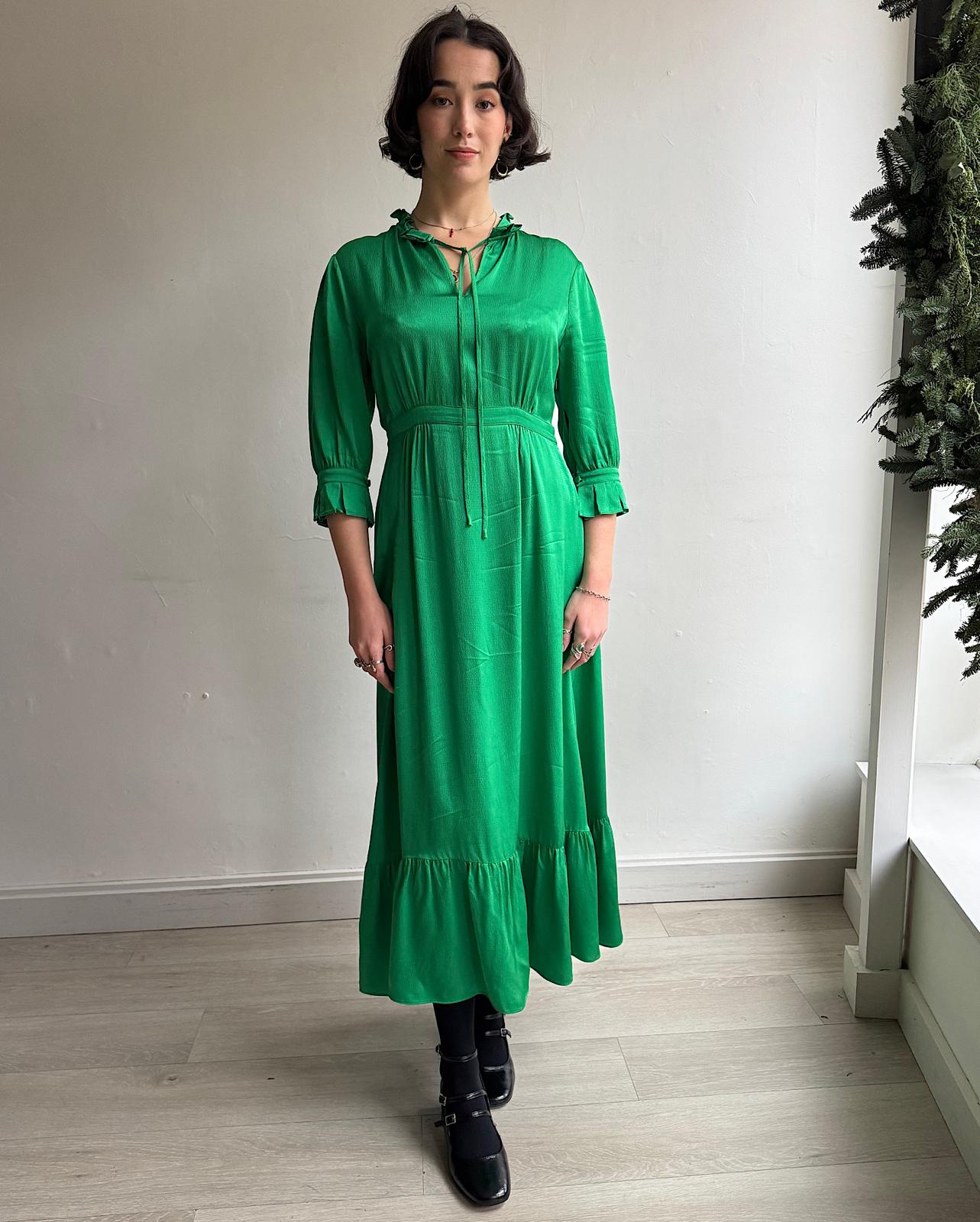 Front view of green 'Evie' dress, designed by Yolke, features cropped pleated sleeves and is trimmed with delicate ruffles at the neckline.