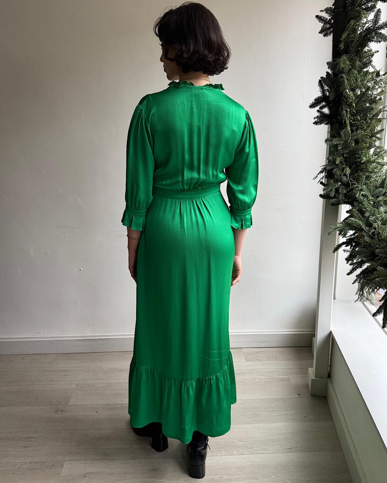 Back view of green 'Evie' dress, designed by Yolke, features cropped pleated sleeves and is trimmed with delicate ruffles at the neckline.