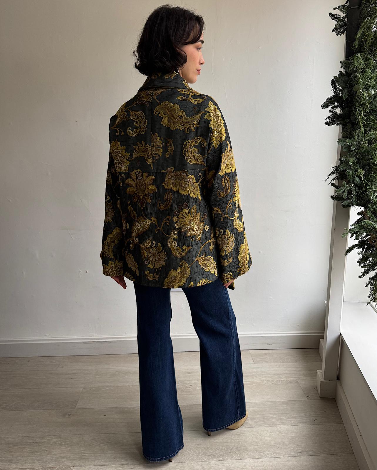 Back view of elegant drape-front jacket by Antonio Marras features a gold pattern on dark green fabric