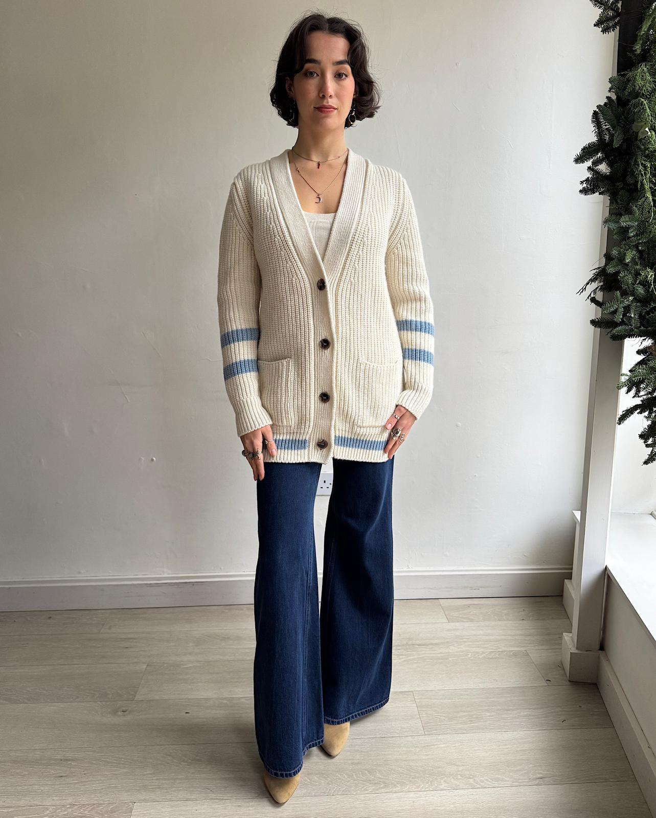 Front view of  cosy cream ribbed wool cardigan by Navygrey features blue stripe details on the arms and hem. 