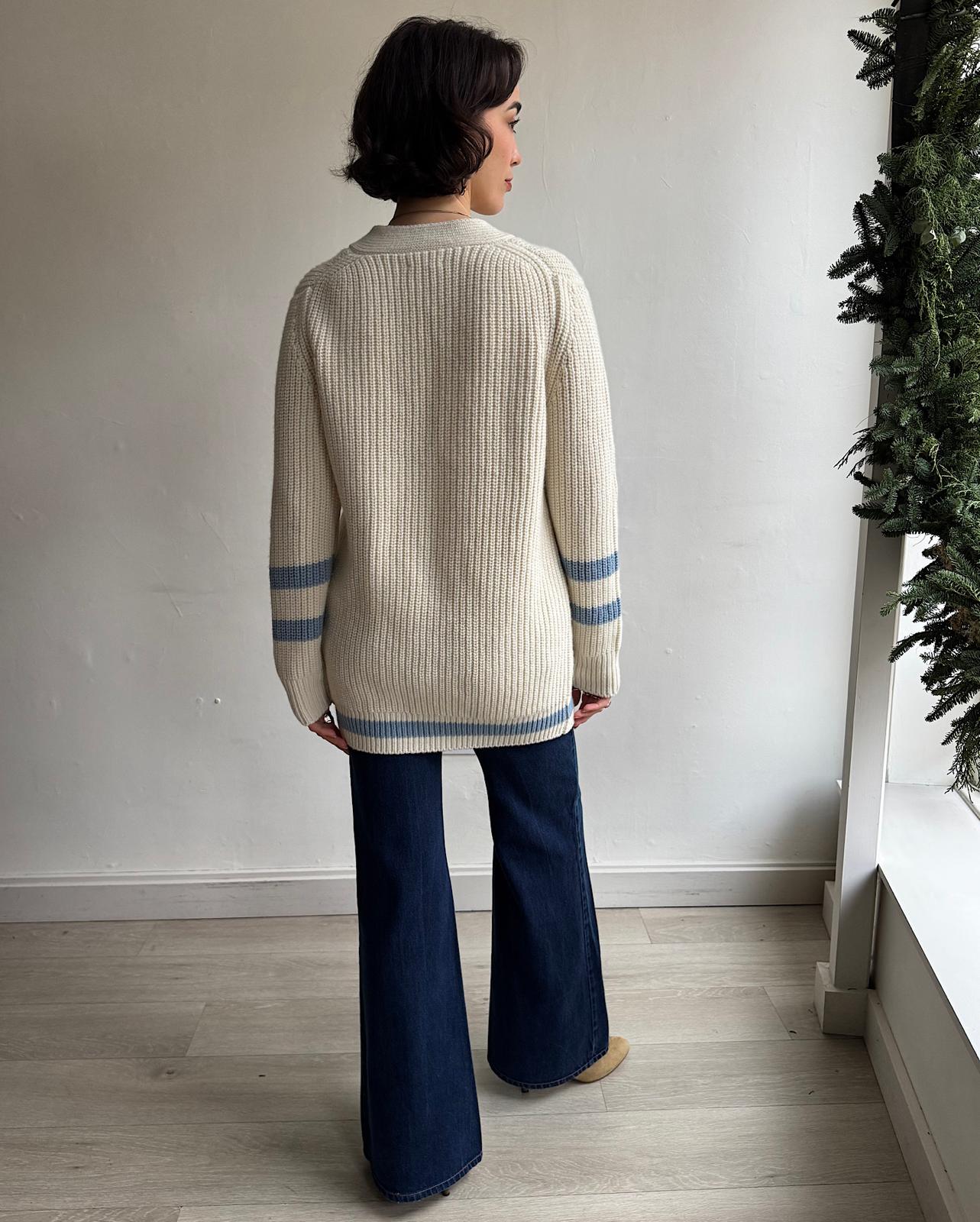 Back view of  cosy cream ribbed wool cardigan by Navygrey features blue stripe details on the arms and hem. 