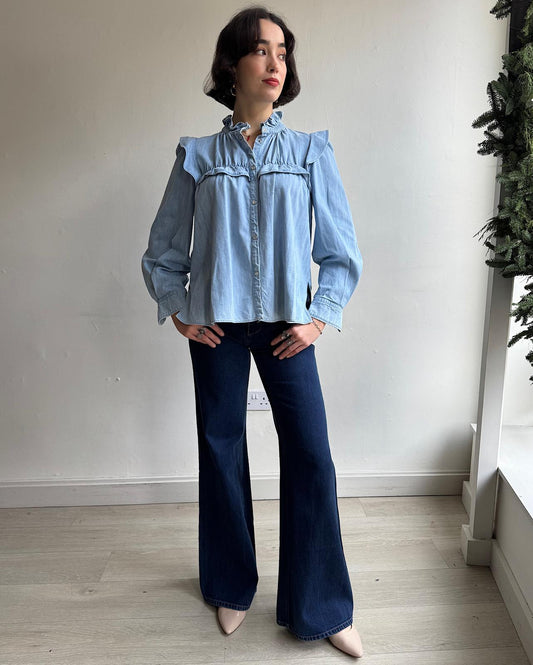 Front view of stunning denim shirt by Isabel Marant Étoile featuring long sleeves, snap fastenings, ruffles, and smocking details.