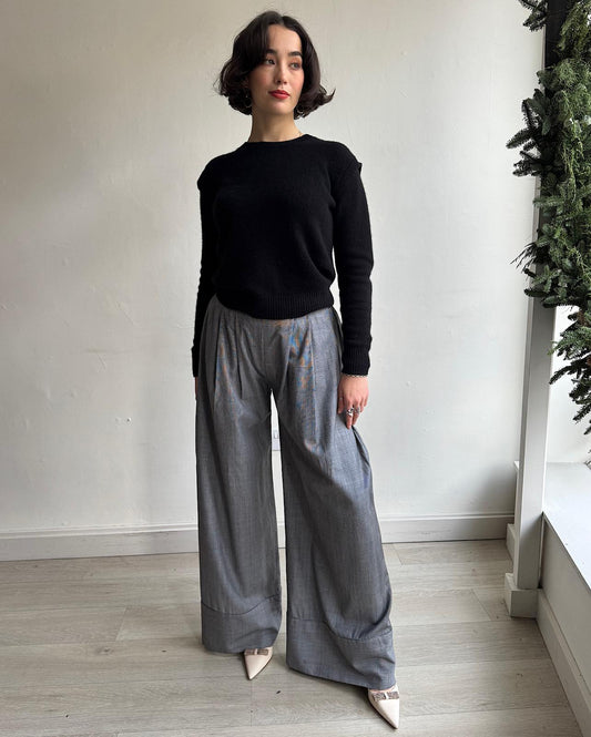 Front view of stunning pair of grey wide-leg check wool trousers by Michael Lo Sordo. They feature an elasticated waistband at the back, a pleated front, and wide cuffs. 