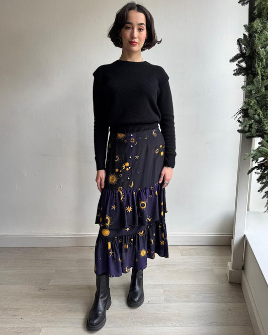 Front view of silk starstruck skirt by Hayley Menzies features a ruffle-tiered design and a constellation-inspired print in navy, black, and gold.