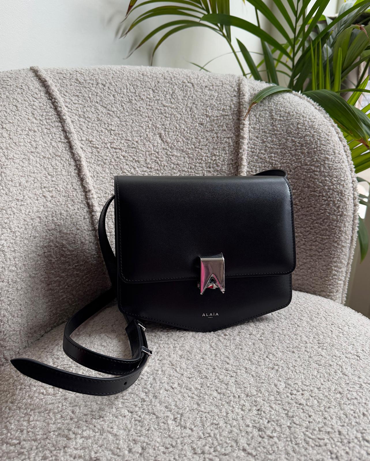 Front view of expertly crafted Le Papa crossbody bag by Alaia features a sleek black leather construction complemented by silver-tone hardware.